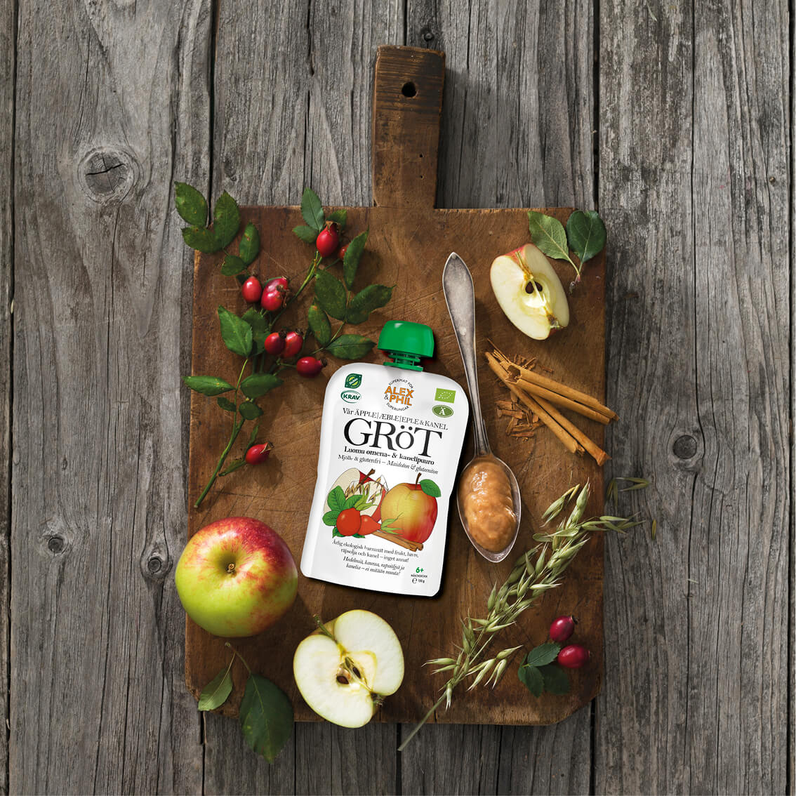 En flaska alexphilfood Äpple- & kanelgröt (5-pack) på en skärbräda av trä, fylld med äpplens naturliga godhet.